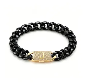 Dettaglio di bracciale a maglia cubana nera con chiusura dorata lettera 'J'