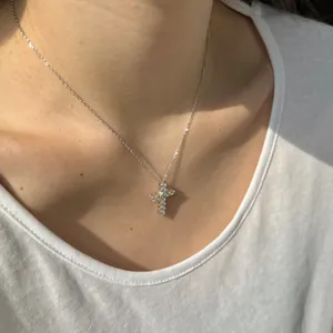 Gros plan d'un collier croix en argent sterling S925 avec moissanites sur le cou d'un mannequin.