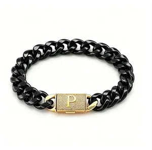 Dettaglio macro di un bracciale a catena nera spessa con chiusura pavé dorata e lettera P