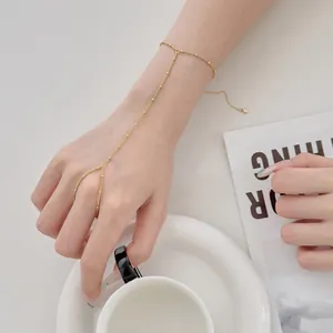 Détail d'un délicat bracelet de doigt en argent S925 avec une chaîne à billes dorées