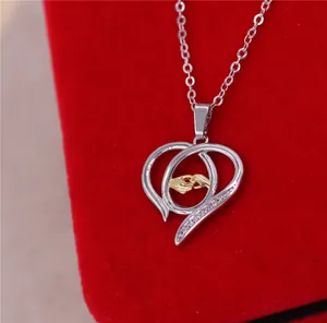 Vista detallada del collar de corazón con manos de madre e hijo en tono dorado