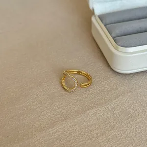 Close-up of a gold-plated irregular ring with sparkling stones on textured background.