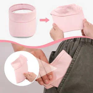 Lightweight pink sun visor hat being folded and tucked into a pocket for portability.