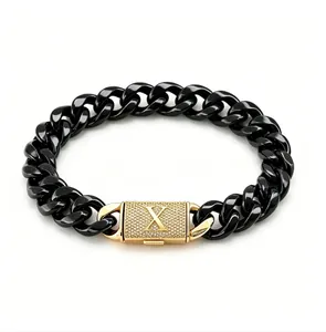 Dettaglio macro del bracciale Cuban in acciaio nero con chiusura in oro pave lettera X