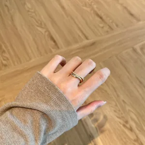 Close-up of a double-layered wavy gold sterling silver ring on a model's finger