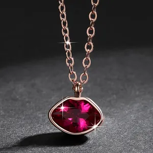 Detailopname van een roségouden ketting met een gefacetteerde rode kristallen lippen hanger