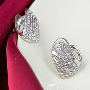 Close-up detail of silver heart-shaped stud earrings with full pavé crystals