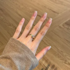 Detail of an irregular wavy gold-plated silver ring with a small cubic zirconia on a finger
