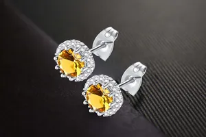 Detailed macro view of yellow zircon stud earrings with sparkling crystal halo setting