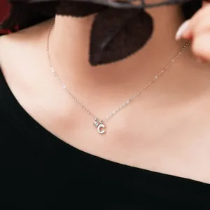 Detail of S925 sterling silver necklace with letter C and gemstone pendant on neck