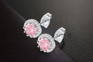 Detail view of silver halo stud earrings featuring sparkling pink zircon center stones.