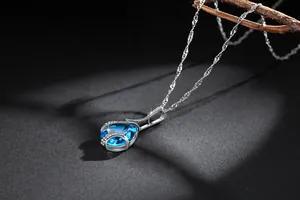 Detailed macro view of a silver necklace featuring a blue teardrop-shaped zircon pendant