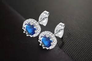 Detail shot of sparkling blue zircon stud earrings with a halo of white crystals.