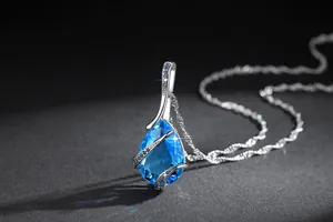 Detailed close-up of a pear-shaped blue topaz zircon pendant on a silver chain
