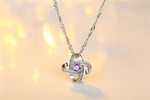 Nahaufnahme einer eleganten Silberkette mit lila Zirkonia-Anhänger in warmem Licht