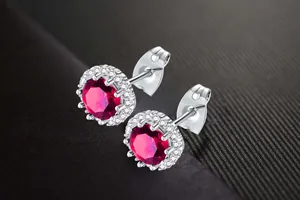 Macro view of silver stud earrings featuring a round red zircon and halo zircon stones
