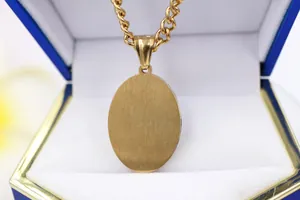 Close-up of the brushed gold-tone finish on an oval pendant in a blue jewelry box.