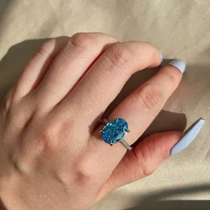 Gedetailleerde weergave van een sterling zilveren ring met ovale blauwe zirkoon op hand.
