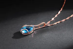 Macro detail of aquamarine water drop pendant with rose gold finish and pavé accents