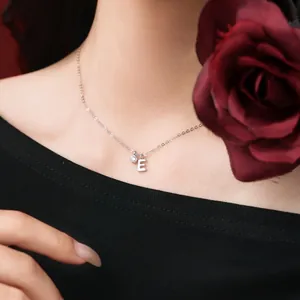 Detail of sterling silver necklace featuring a letter E pendant and crystal