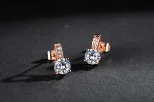 Nahaufnahme von Roségold-Ohrsteckern in Ausrufezeichen-Form mit Zirkonia-Steinen.