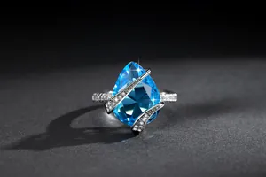 Primo piano di un anello vintage con gemma blu a forma di pera e pavé scintillante.