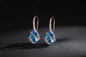 Macro view of elegant sea blue teardrop earrings with zircon on rose gold hooks