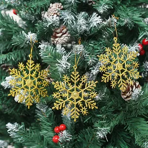 Nahaufnahme von drei goldenen Schneeflocken-Anhängern an einem Weihnachtsbaum