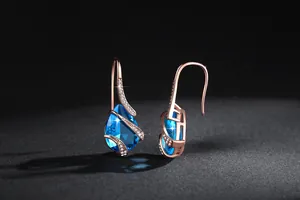 Detailed view of rose gold pear-shaped earrings with blue zircon and pavé crystals