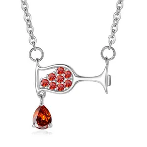 Macro detail of silver necklace featuring a wine glass pendant with red zirconia