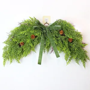 Detailed view of lush artificial pine wreath with green velvet bow and pine cones.