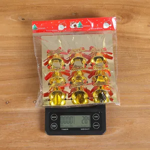 Detail view of 9-pack gold Christmas bells with red bows on a digital scale 28.4g.