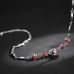 Macro detail of silver bracelet with sparkling heart-shaped red zircon stones.