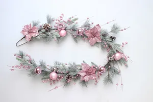 Detailed view of pink Christmas garland with poinsettias, baubles, and snow-dusted pine needles