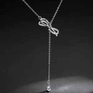 Close-up detail of elegant silver bow-tie necklace featuring a dangling zircon tassel