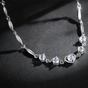 Close-up of heart-shaped charm and sparkling zircon stones on a silver-toned bracelet