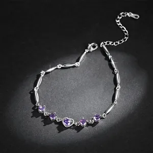 Detailed view of silver heart bracelet with sparkling purple zircons on dark background