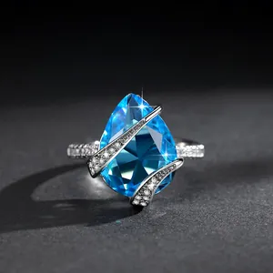 Anello vintage con zircone blu a goccia e dettagli scintillanti su sfondo nero.
