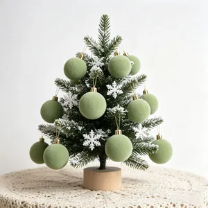 Vista ravvicinata di palline di Natale floccate verde salvia su un albero innevato