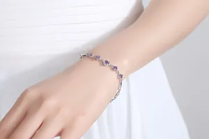 Detailed shot of an elegant silver bracelet with purple heart zircons on a wrist.