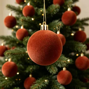 Primo piano di una pallina di Natale floccata arancione bruciato su un albero festivo.