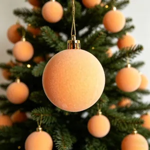 Dettaglio di palline di Natale floccate color pesca appese ai rami dell'albero