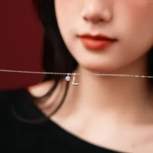 Detailed shot of a S925 silver necklace with a letter L pendant and small sparkling stone