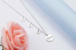 Detail of stainless steel necklace with Mom pendant and child silhouette charms