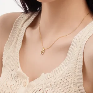 Model wearing a dainty S925 sterling silver gold necklace with a pavé letter F pendant detail