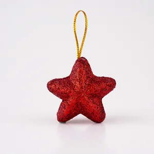 Vista detallada de un adorno navideño de estrella con purpurina roja y lazo dorado.