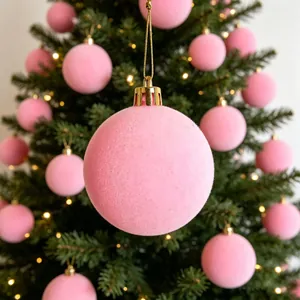 Primo piano di una palla di Natale rosa floccata appesa a un albero festivo decorato