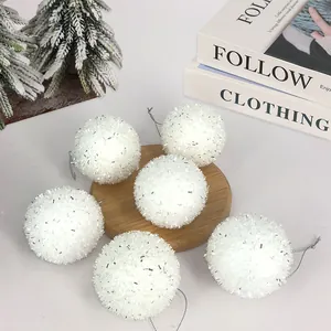 Détail de boules de Noël blanches duveteuses avec paillettes argentées sur bois.