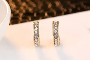 Detalle de pendientes de aro dorados con cristales brillantes engastados en carril