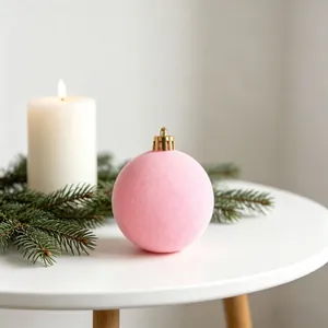 Dettaglio di una pallina di Natale rosa floccata su un tavolo festivo con pino